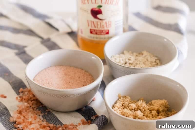 Three white bowls of salt, sugar, and oatmeal scalp scrub.