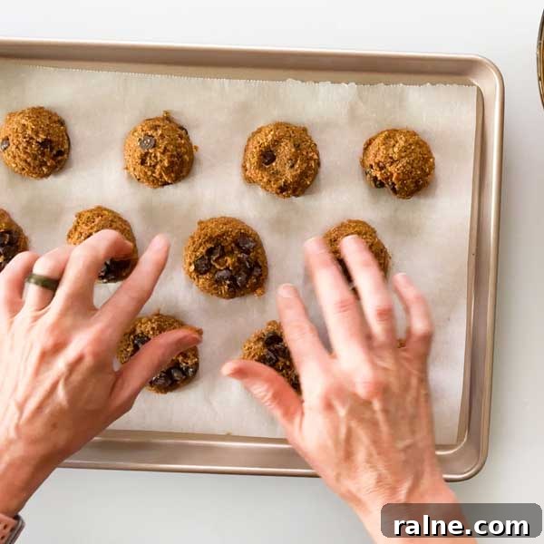 Vegan Gluten-Free Pumpkin Chocolate Chip Cookies 5 Pressing additional chocolate chips into the top of the cookie dough balls on a cookie sheet.
