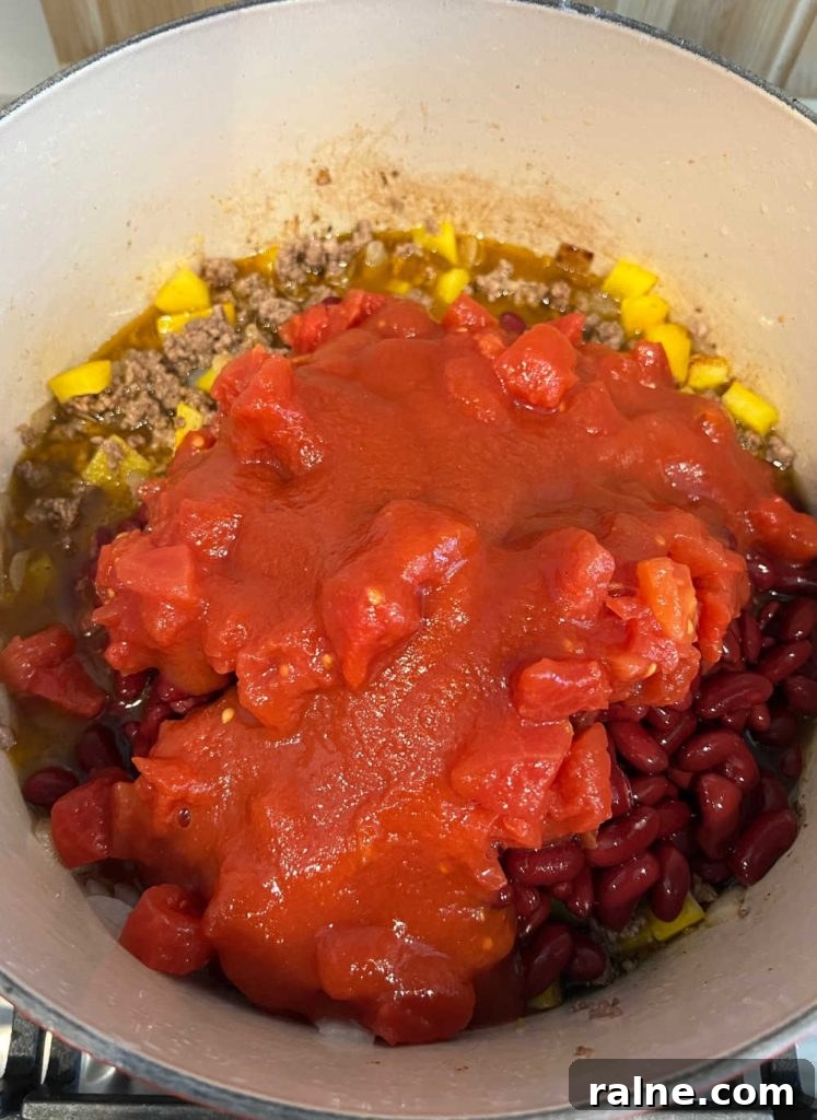 Classic Stove-Top Mom’s Chili Recipe for Weeknight Dinners 6 ground beef, peppers, kidney beans and tomatoes in dutch oven on stovetop