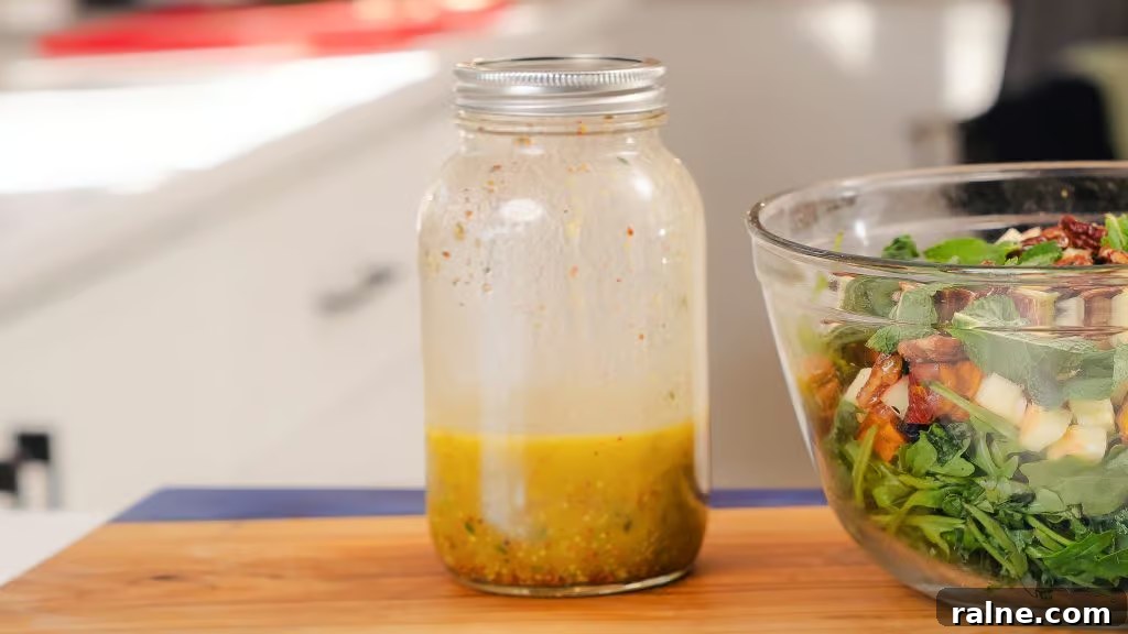Lemon Thyme Vinaigrette Recipe — Bright Citrus Herb Dressing 4 A fully shaken Lemon Thyme Vinaigrette sitting next to a bowl of salad greens.