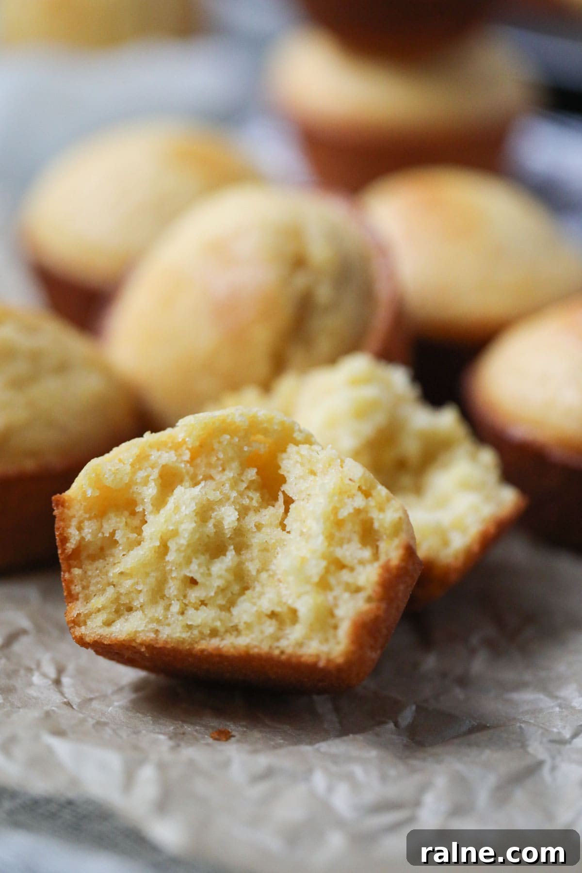 buttermilk cornbread muffin sliced open to show texture on parchment paper.