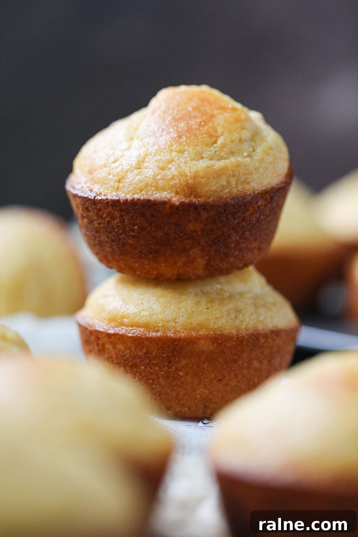 buttermilk cornbread muffins stacked on parchment paper.