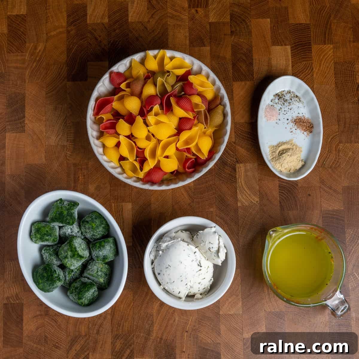 Photo of the ingredients to make quick vegan creamy spinach pasta all set out in bowls on a wooden tabletop.