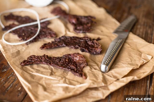 Salt and pepper beef jerky recipe for a savoury snack Salt and Pepper Beef Jerky using jerky on brown paper with string and a fluted cooks knife