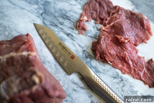 Preparing meat to make jerky Thinly sliced beef for jerky with a knife on a marble board