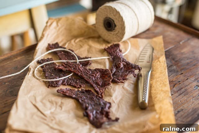 Beef jerky recipe : No nitrates, no marinade Salt and Pepper Beef Jerky on brown paper with string and a fluted cooks knife