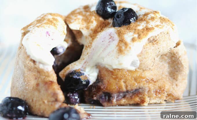 Single-Serve Blueberry Cinnamon Roll Recipe 3 Close-up of the inside of a cinnamon roll with blueberries and cream cheese frosting.