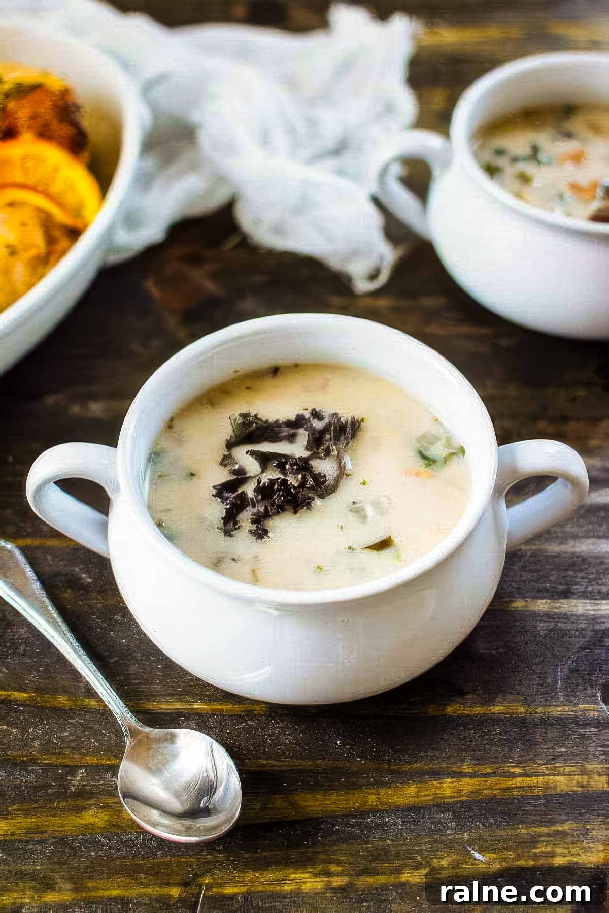 Creamy Cannellini Bean and Kale Soup Recipe for Cozy Nights 3 two white bowls of cannellini bean and kale soup on a rustic wood table next to roasted chicken for dinner