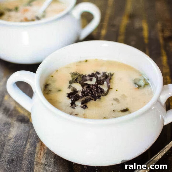 two white bowls of cannellini bean and kale soup on a rustic wood table
