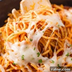 Slow-Cooker Spaghetti with Savory Meat Sauce 11 Close-up of spaghetti with melted cheese and herbs, twirled around a fork.