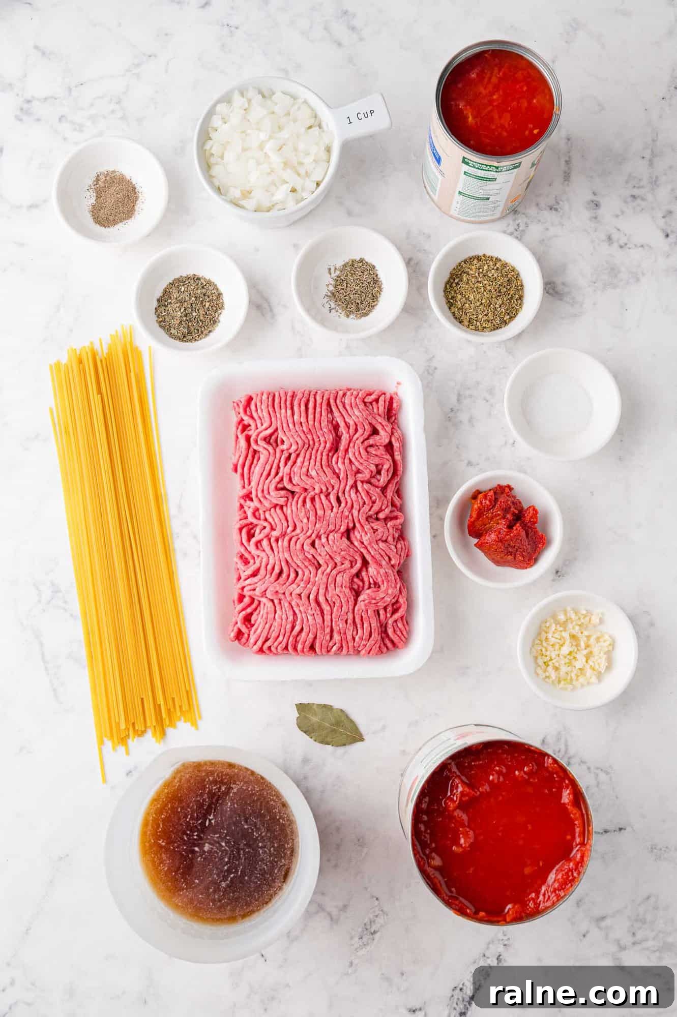 Slow-Cooker Spaghetti with Savory Meat Sauce 4 Ingredients for spaghetti on a marble surface, including ground meat, tomatoes, and more.