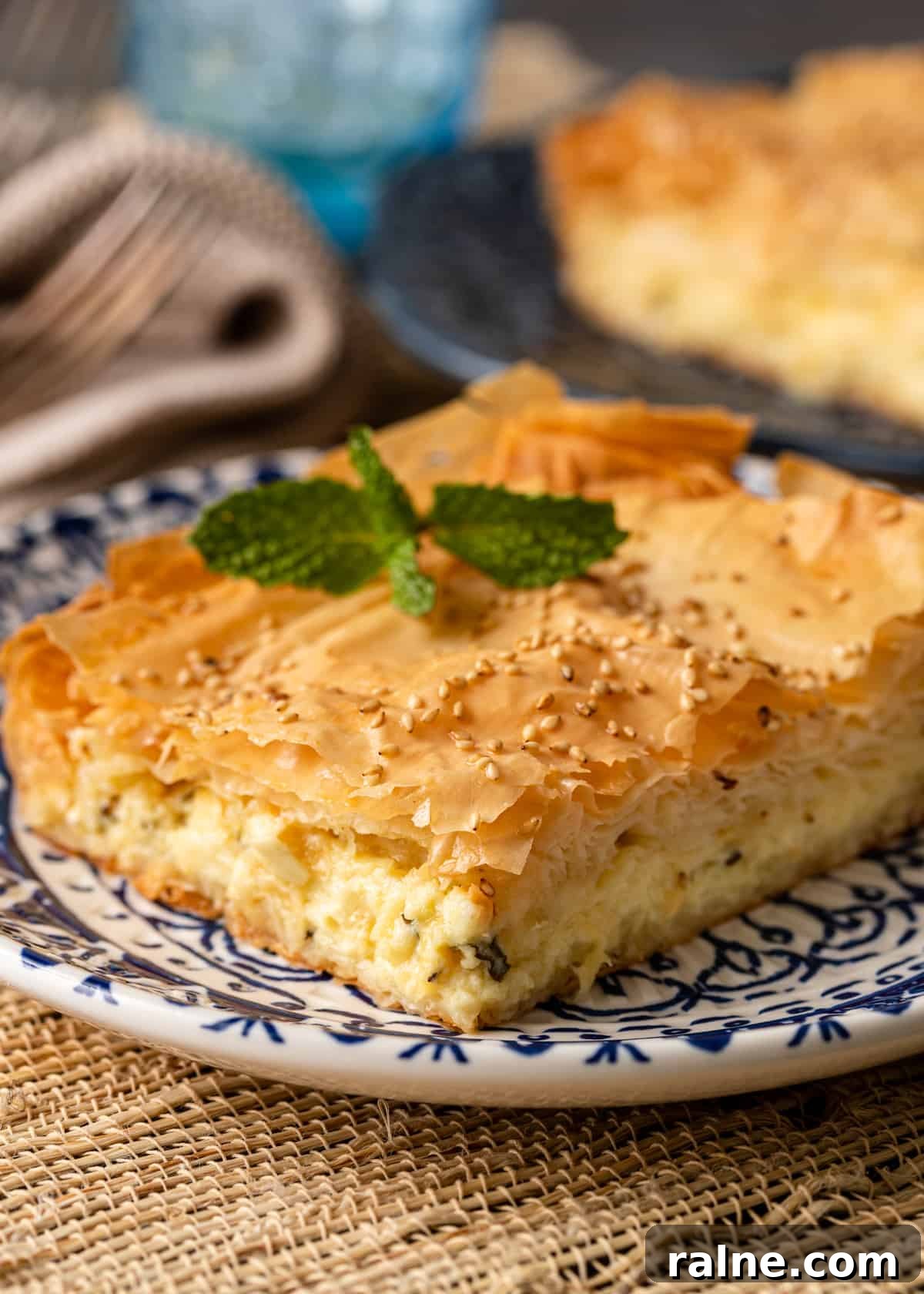 Tiropita: Authentic Greek Cheese Pie Recipe & Tips 14 closeup: plate with a piece of grek cheese pie with mint sprig on top