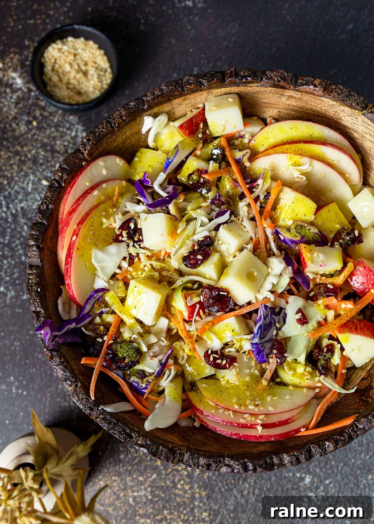 Asian Cabbage and Apple Slaw with Tangy Dressing 13 Sweet and sour cabbage apple salad in a bowl with cheese, craisins, and toasted sesame seeds.