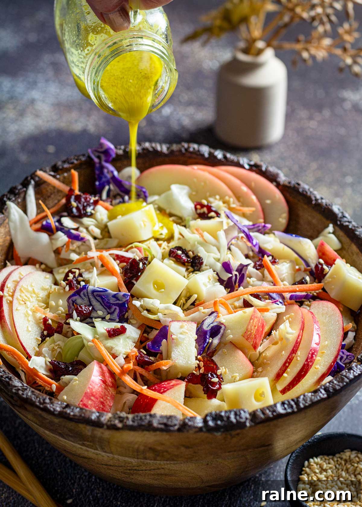 Asian Cabbage and Apple Slaw with Tangy Dressing 8 Pouring dressing over cabbage slaw with apples and Swiss cheese.