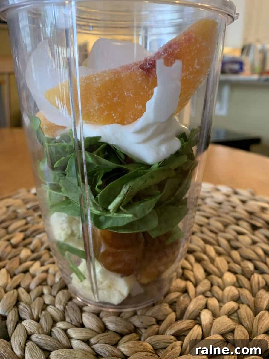 Refreshing Sweet Green Smoothie Recipe for Energy and Glow 8 Peach slices on top of smoothie ingredients in a blender cup