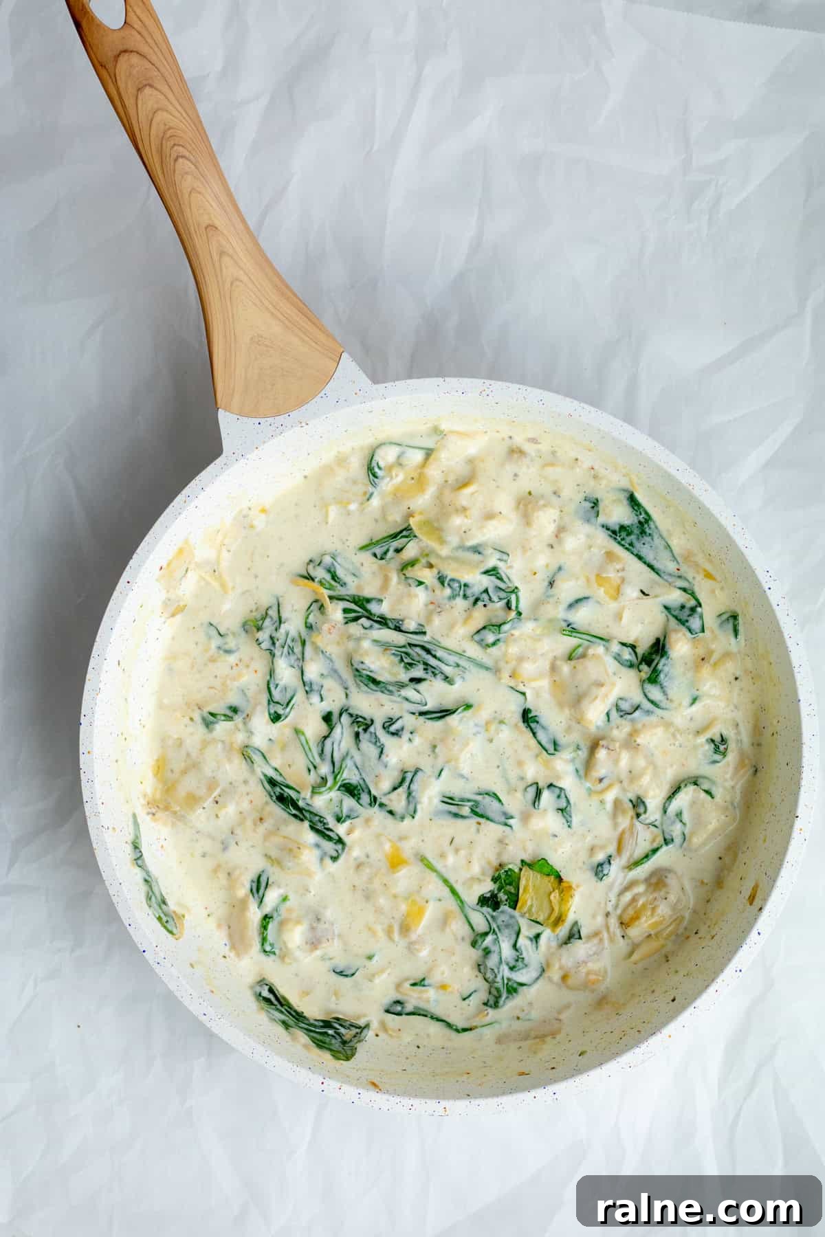 sauce for past with spinach and artichokes mixed together in pan