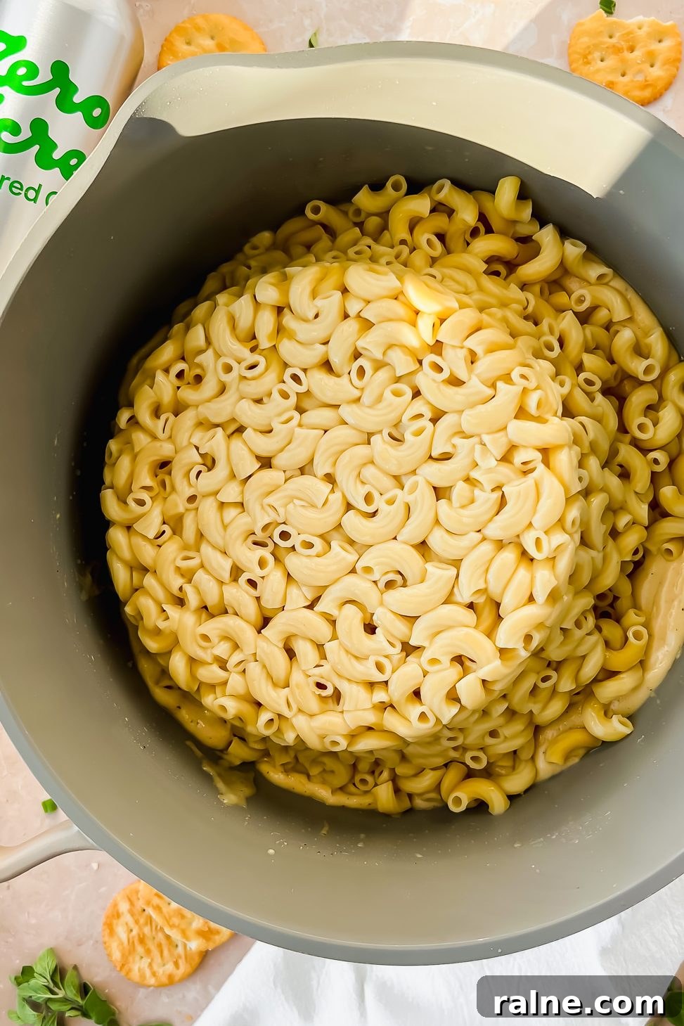 tan pot full of elbow noodles beside bottle of Zero Acre cultured oil.