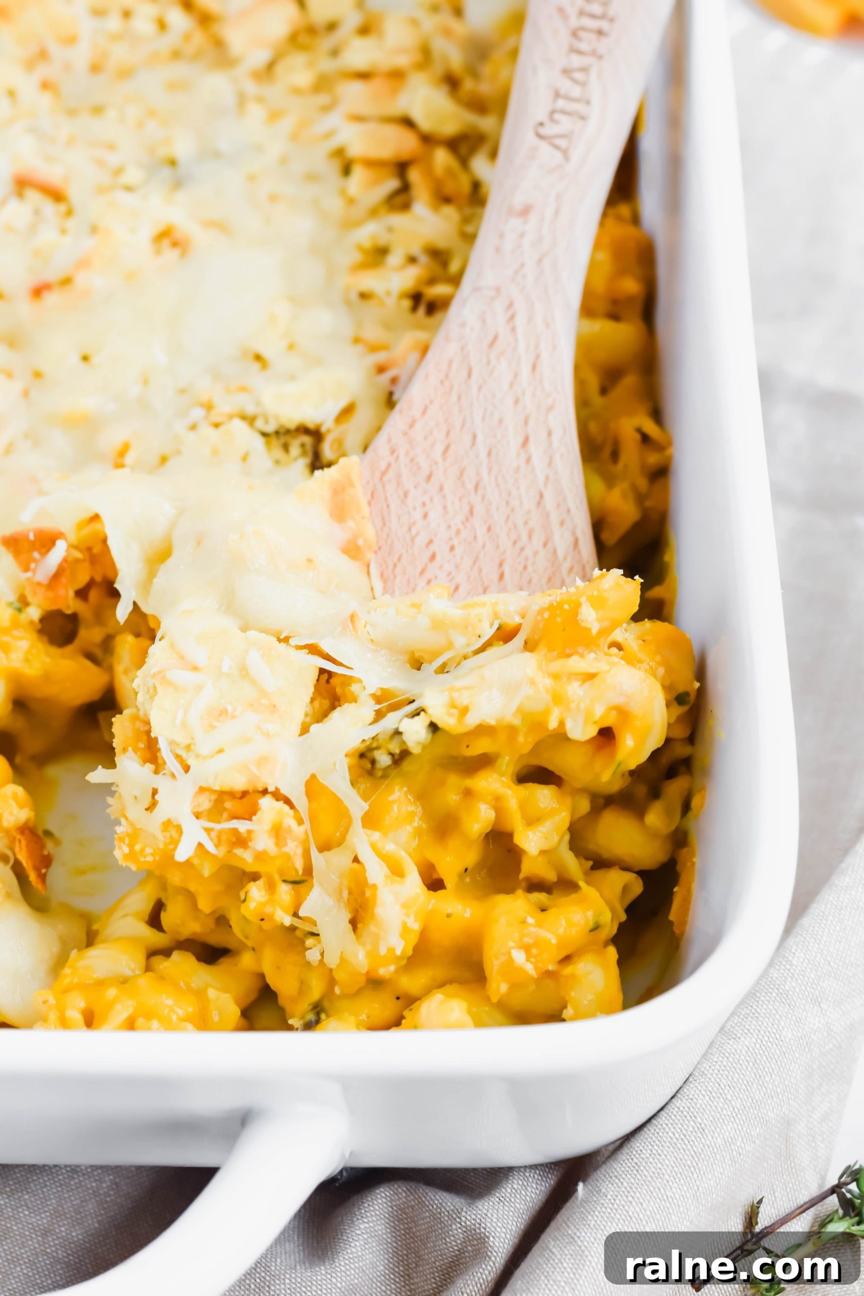Butternut Squash Mac and Cheese with Trader Joe's Crackers in white baking dish with wooden spoon.
