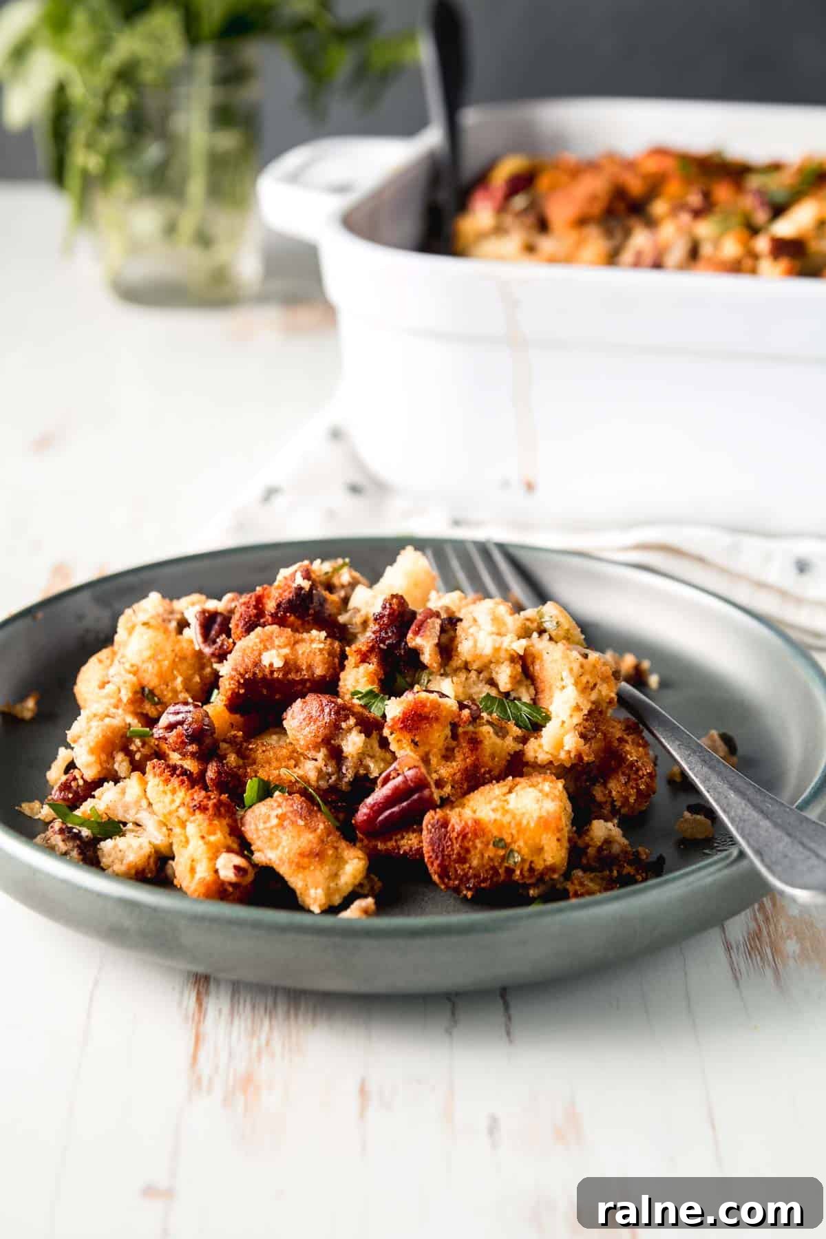 Gluten-Free Cornbread Stuffing with Sausage and Apples for Holiday Meals 6 A scoop of stuffing on a green plate sprinkled with pecans and fresh herbs.