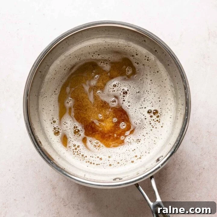 Brown butter with deep golden toasted milk solids visible beneath the foam in a saucepan.