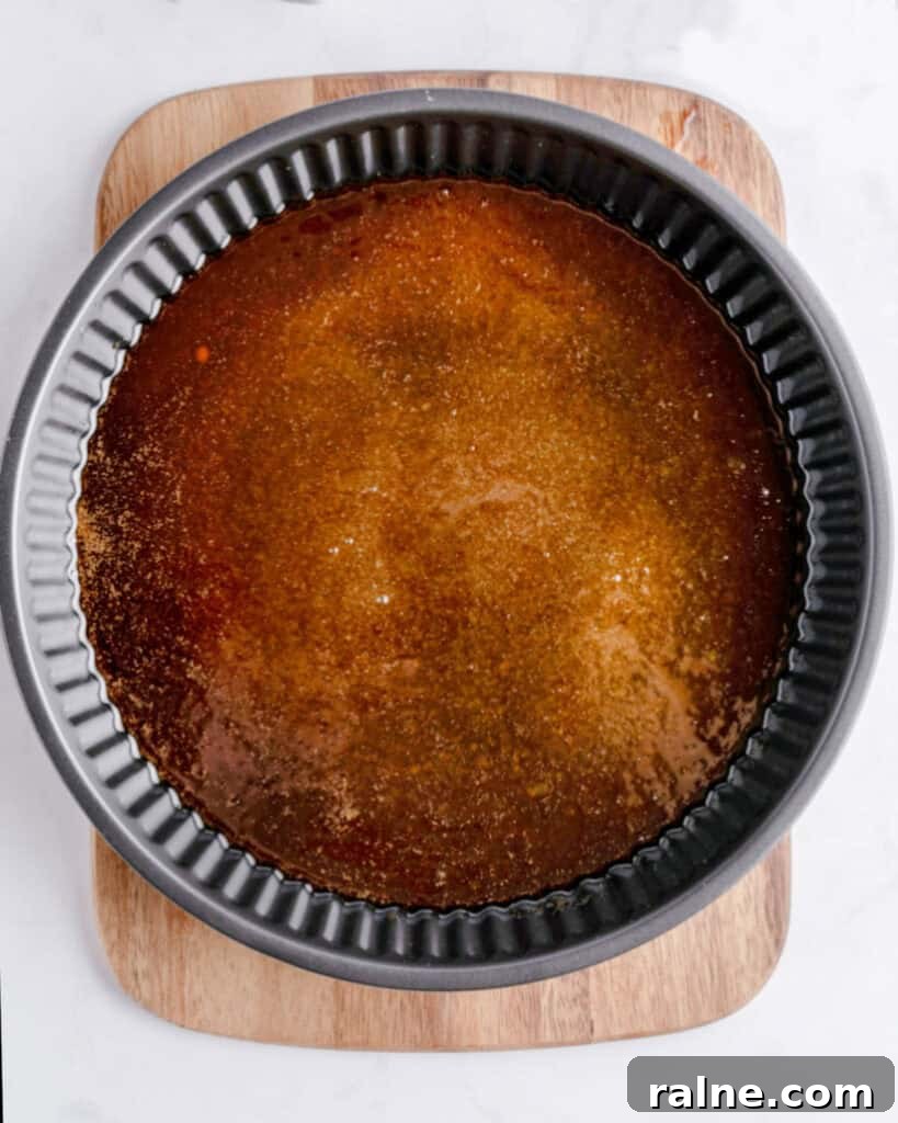 Caramel on a black round  metal pan. Wooden board. Top view. Light gray surface. 