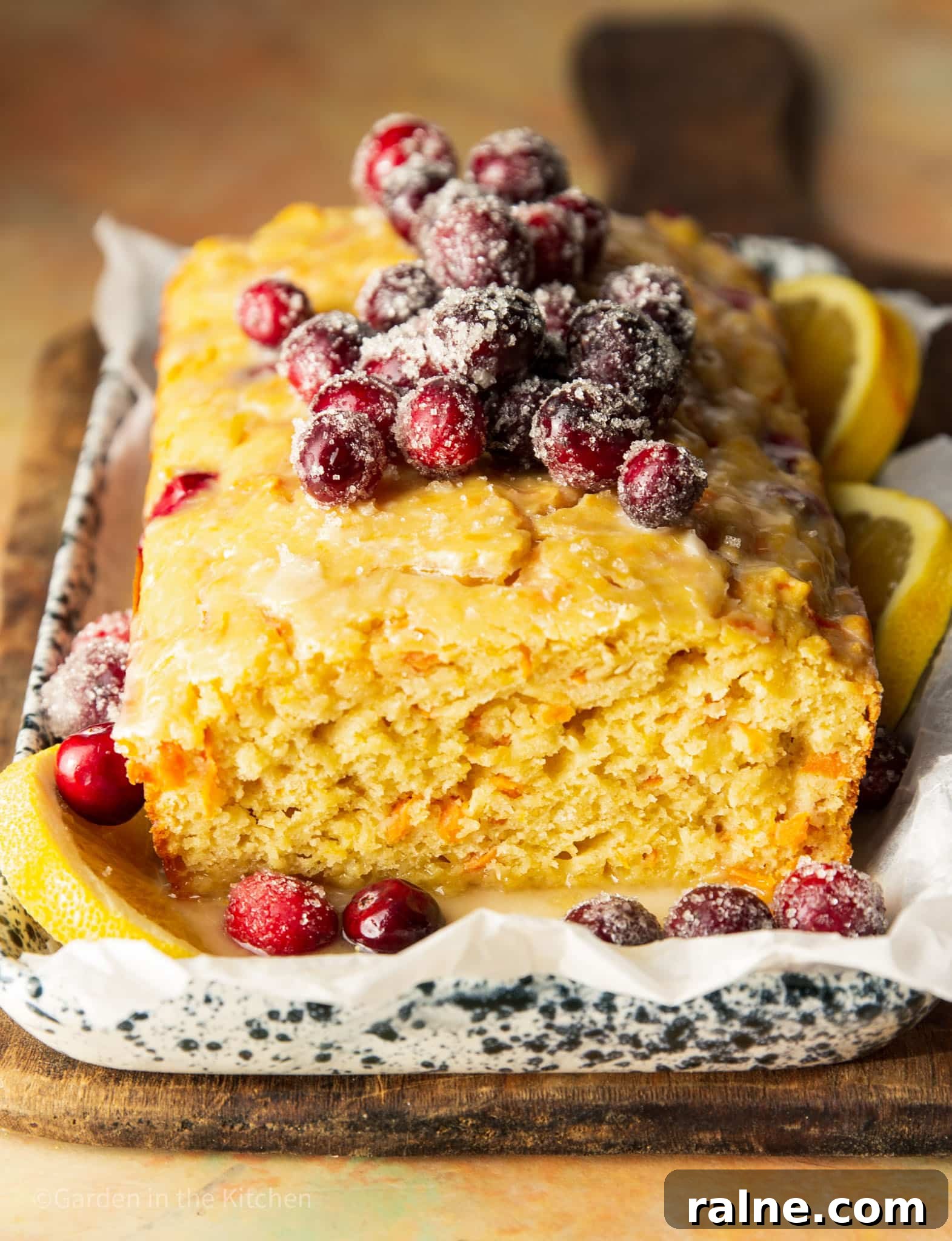 Cranberry Orange Carrot Cake Recipe with Zesty Glaze 5 close up on a baked cranberry orange carrot cake topped with sugared cranberries.