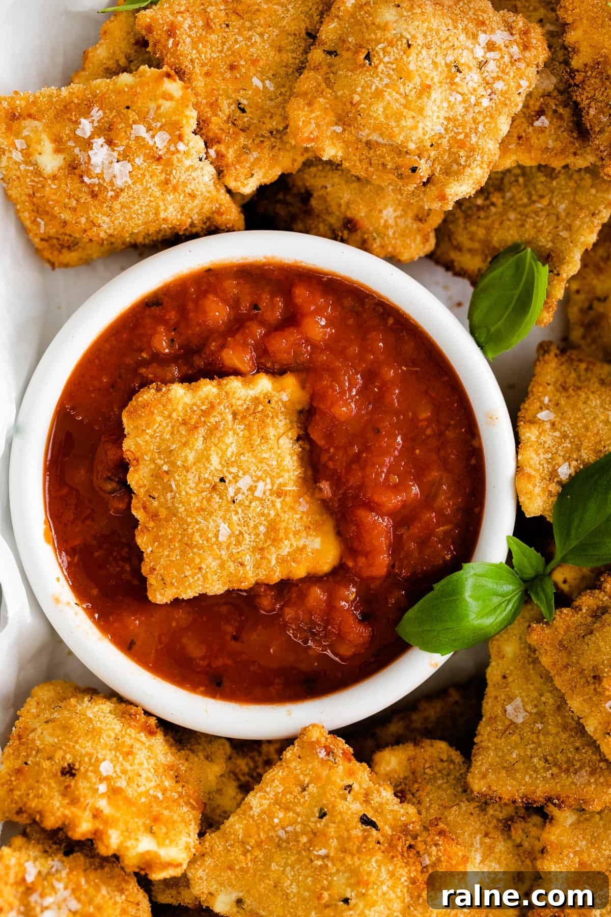 Crispy Air Fryer Ravioli Recipe — Quick Golden Bites 6 A ravioli sitting in marinara sauce.