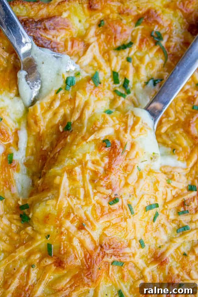 Ina Garten’s Make-Ahead Mashed Potatoes Recipe for Gatherings 4 Cheesy make ahead mashed potatoes in a large pan with serving spoons.