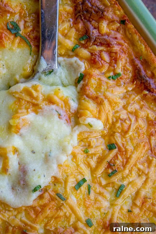 Ina Garten’s Make-Ahead Mashed Potatoes Recipe for Gatherings 6 Golden brown mashed potatoes in a large pan with spoon.