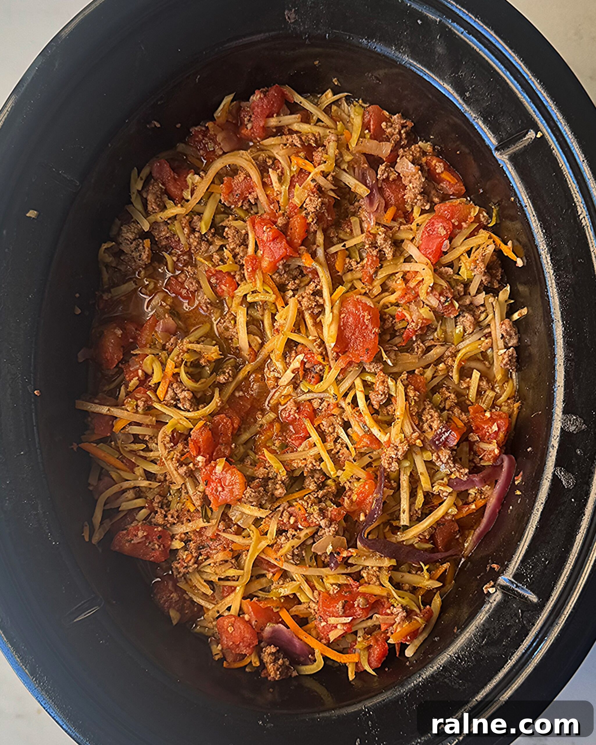 overhead shot of cooked slawghetti in a black slow cooker