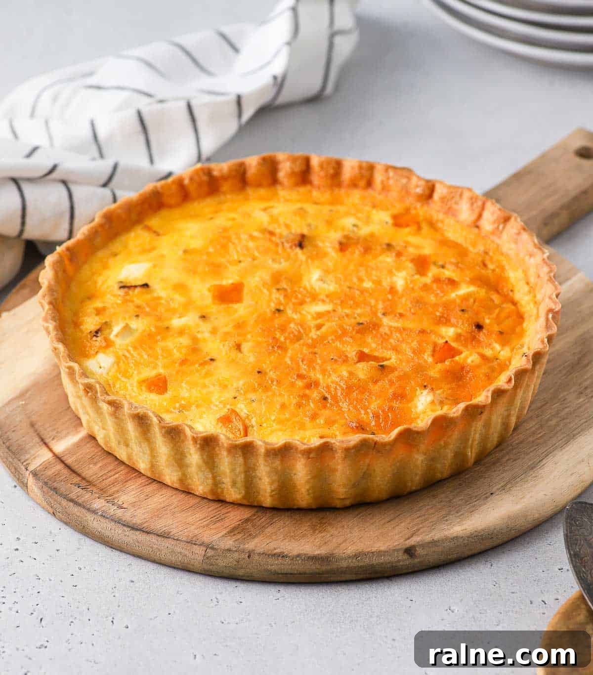 Roasted Pumpkin and Sage Quiche with Flaky Pie Crust 6 Quiche on a wooden round board.