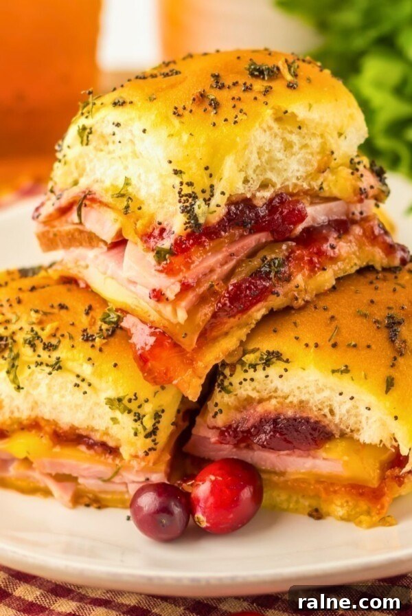 Cheesy Garlic Stuffed Mushrooms with Herb Breadcrumbs 11 Cranberry and ham sliders stacked on a white plate with red cranberries as a garnish.