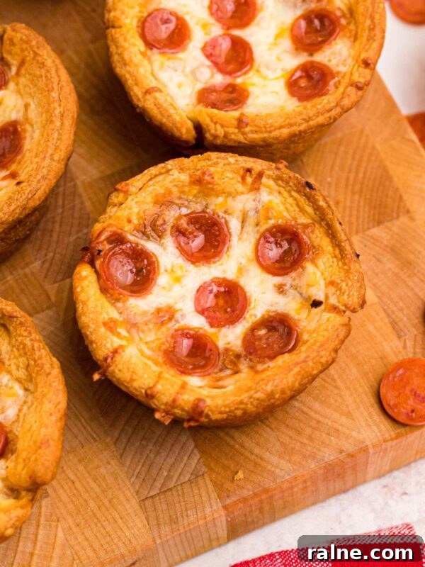 Cheesy Garlic Stuffed Mushrooms with Herb Breadcrumbs 13 Golden crusted pizza cupcakes on a wooden cutting board with pepperoni scattered around the table.