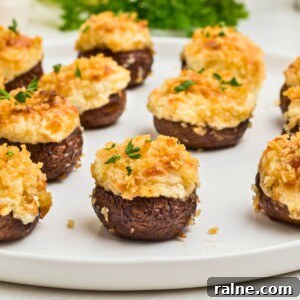 Cheesy Garlic Stuffed Mushrooms with Herb Breadcrumbs 15 Brown mushrooms topped with cream cheese mixture and breadcrumbs, on a white plate.
