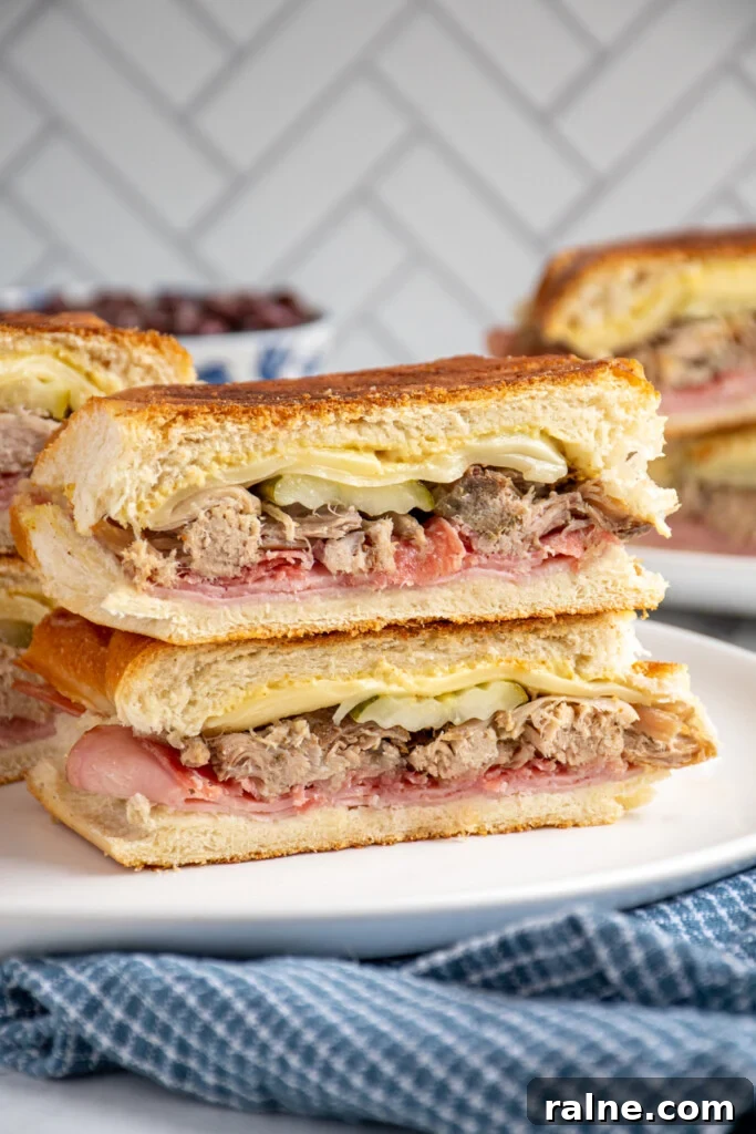 How to Make an Authentic Cuban Sandwich at Home 2 A Cuban sandwich sliced in half and stacked on top of one another showing the ingredients on the inside.