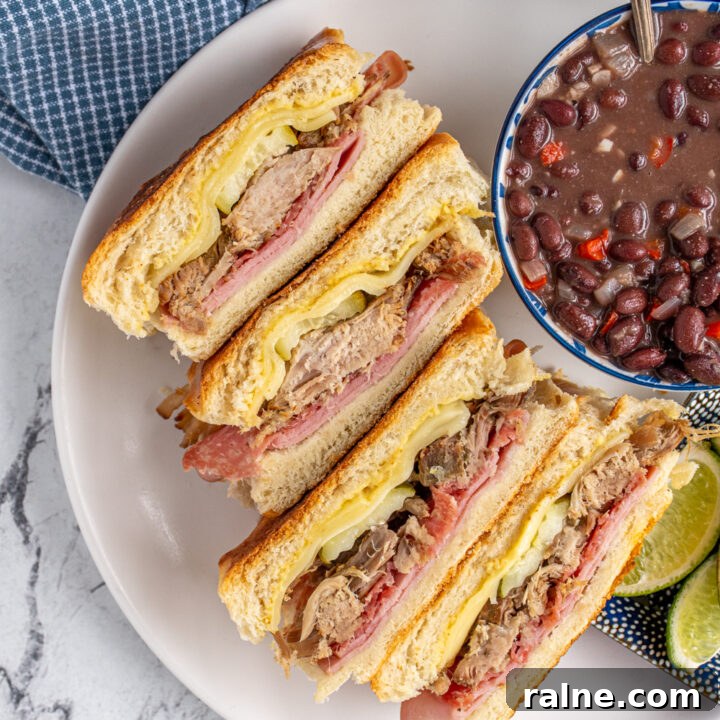 Overhead view of cut open cuban sandwiches revealing the ingredients on the inside.