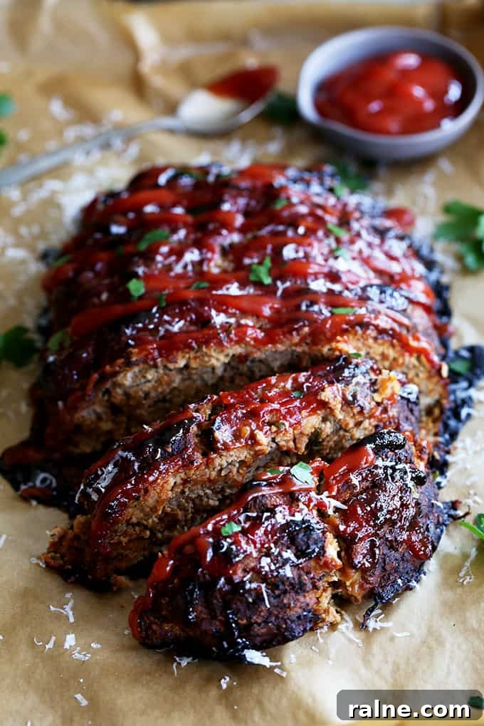 Turkey Meatloaf A Turkey Meatloaf being sliced on a parchment lined baking sheet with a spoon and bowl of ketchup.