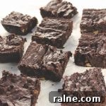 Squares of Fudgy Double Chocolate Brownies on a white parchment paper