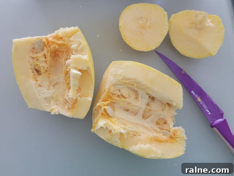 Crispy Air Fryer Spaghetti Squash with Garlic Parmesan 4 cut spaghetti squash next to a purple knife on a cutting board.