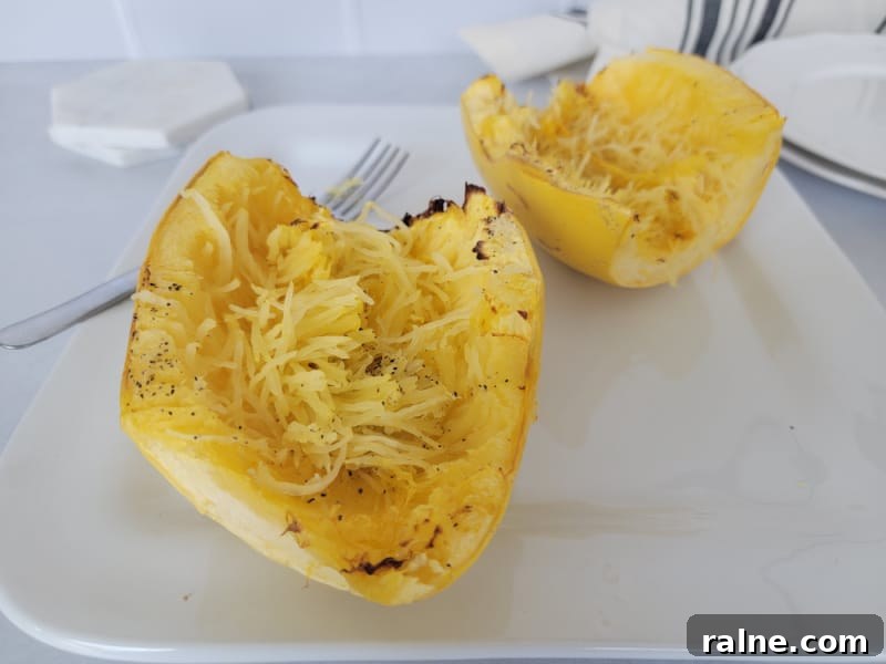 Crispy Air Fryer Spaghetti Squash with Garlic Parmesan 8 air fryer spaghetti squash next to a fork on a white plate.