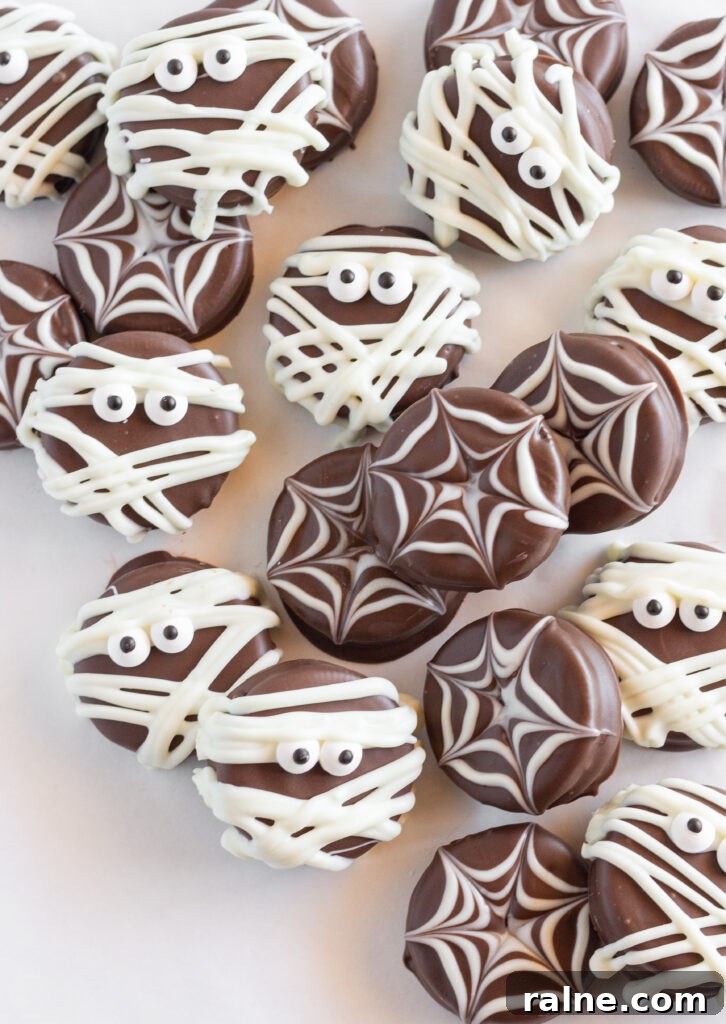 A bunch of spider and mummy Chocolate Covered Oreo Cookies on a large tray.