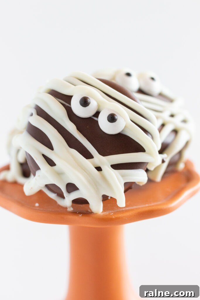 A few Chocolate Covered Oreo Mummies on an orange cake plate.