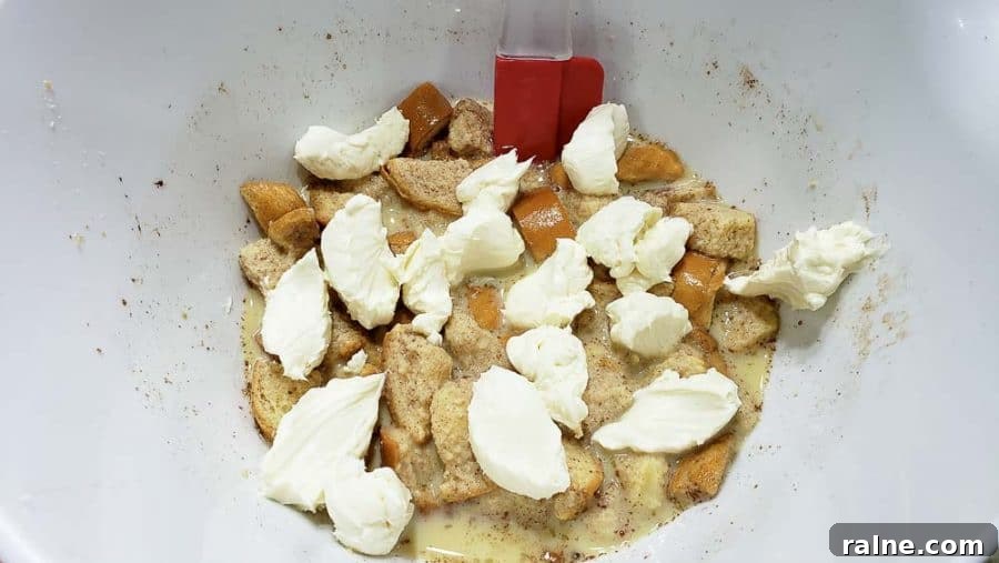 spoonful's of cream cheese mixture dropped into bowl with bread mixture.