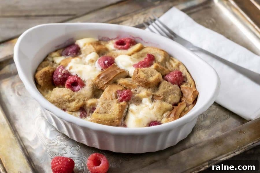 Raspberry Cream Cheese French Toast Casserole in a dish on a tray with a fork and napkin.