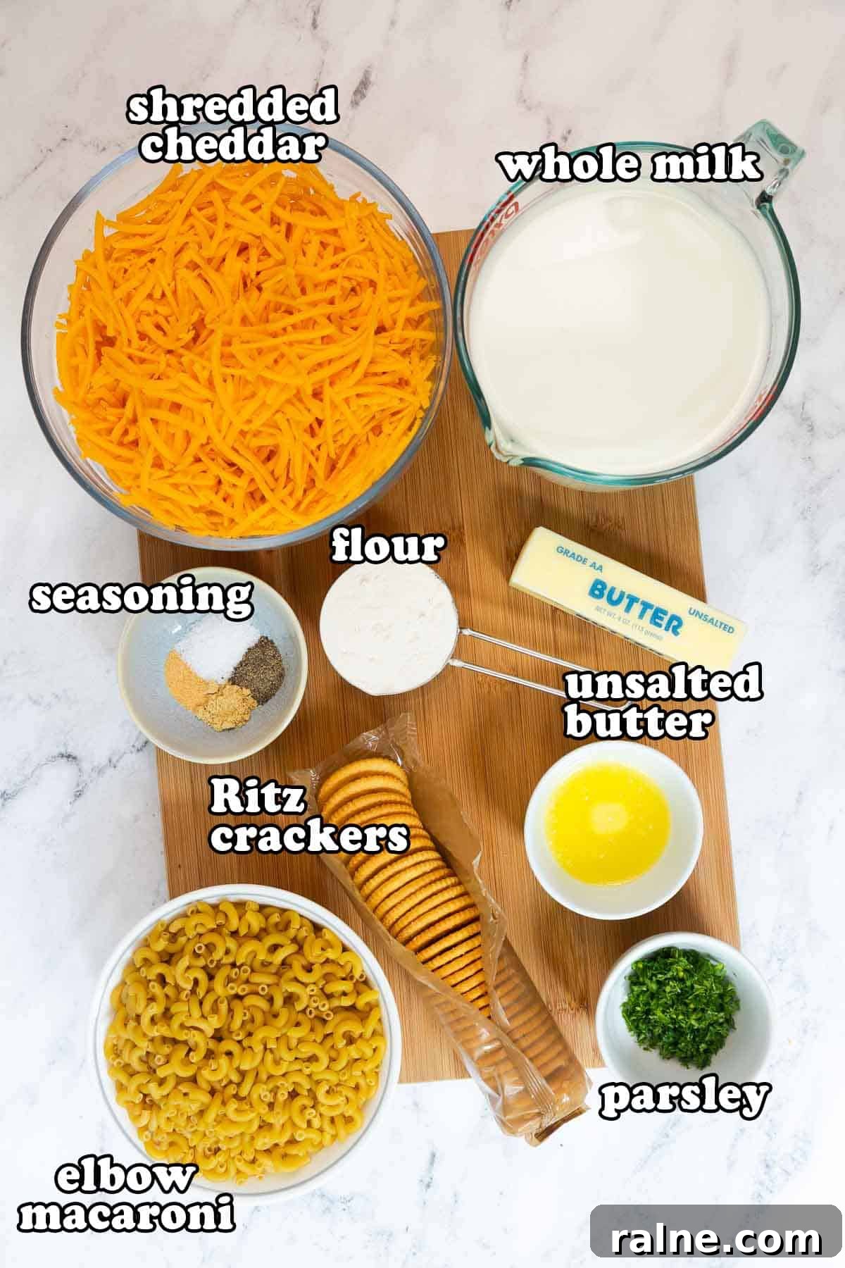 Old-Fashioned Baked Mac and Cheese with Ritz Cracker Topping 3 Ingredients for old fashioned baked mac and cheese with Ritz crackers displayed on a wooden board, including shredded cheddar, whole milk, unsalted butter, flour, elbow macaroni, Ritz crackers, seasoning, and parsley.