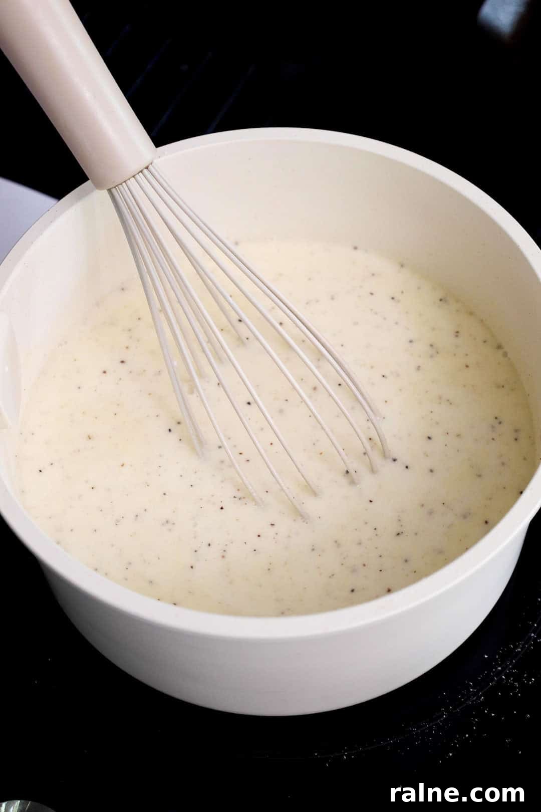 Old-Fashioned Baked Mac and Cheese with Ritz Cracker Topping 5 Flour and seasoning whisked into milk to create a béchamel-style base in a white saucepan during the early stages of making mac and cheese sauce.