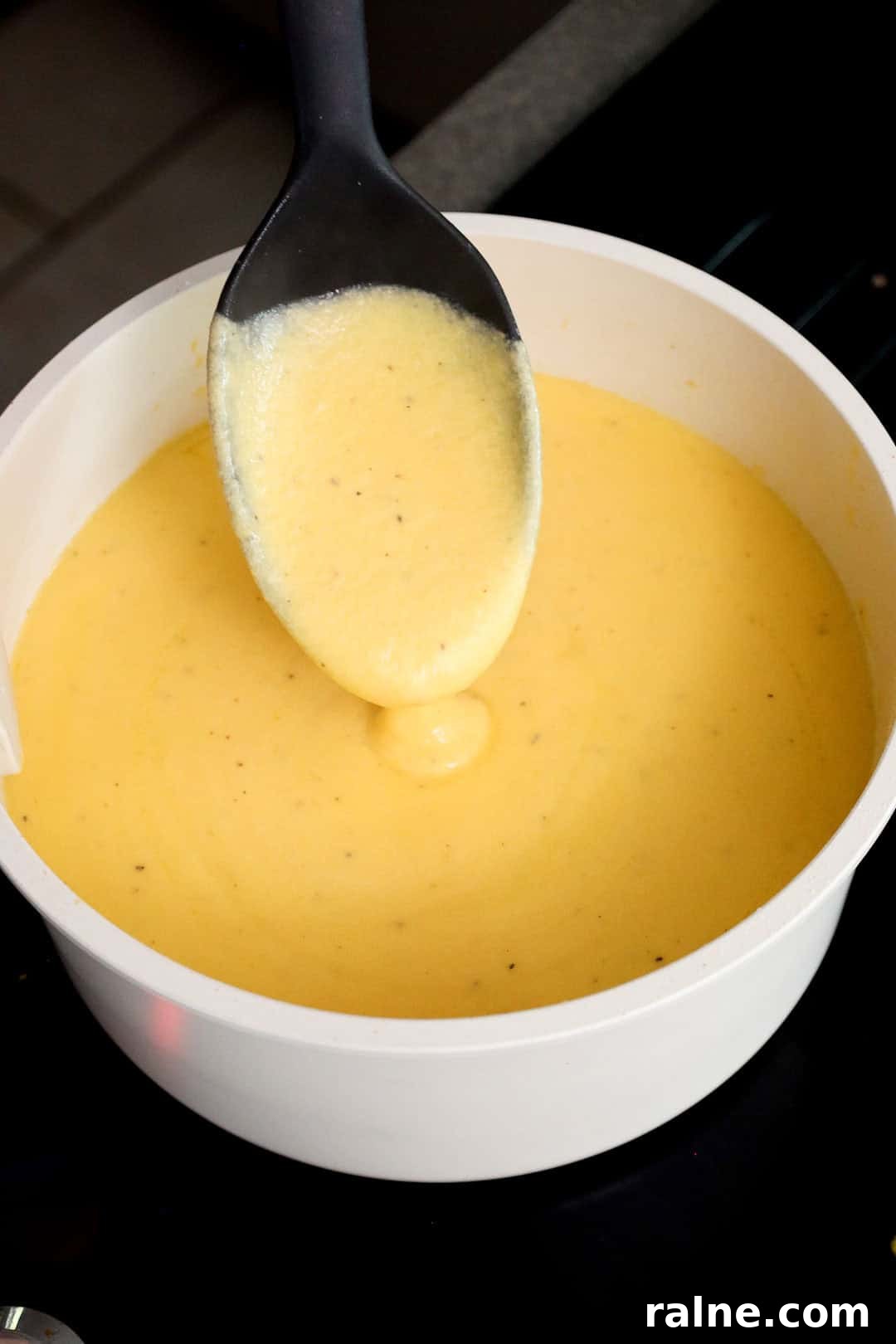 Old-Fashioned Baked Mac and Cheese with Ritz Cracker Topping 6 Thick, creamy cheese sauce made from shredded cheddar and milk being stirred with a spoon in a saucepan.