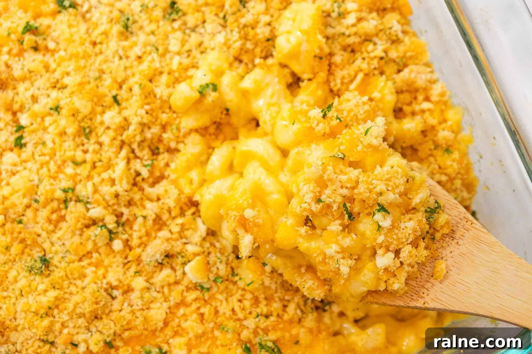 Old-Fashioned Baked Mac and Cheese with Ritz Cracker Topping 10 Wooden spoon scooping creamy cheddar mac and cheese topped with crumbled cracker topping out of a casserole dish.