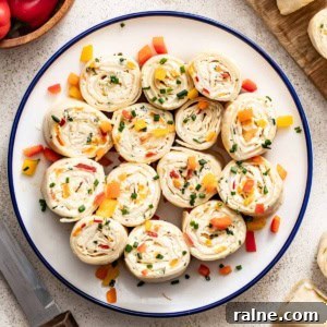 Cream Cheese Tortilla Roll-Ups: 5-Minute Party Appetizer Recipe 13 A plate of vegetable tortilla pinwheels with cream cheese and a bowl of peppers next to them.