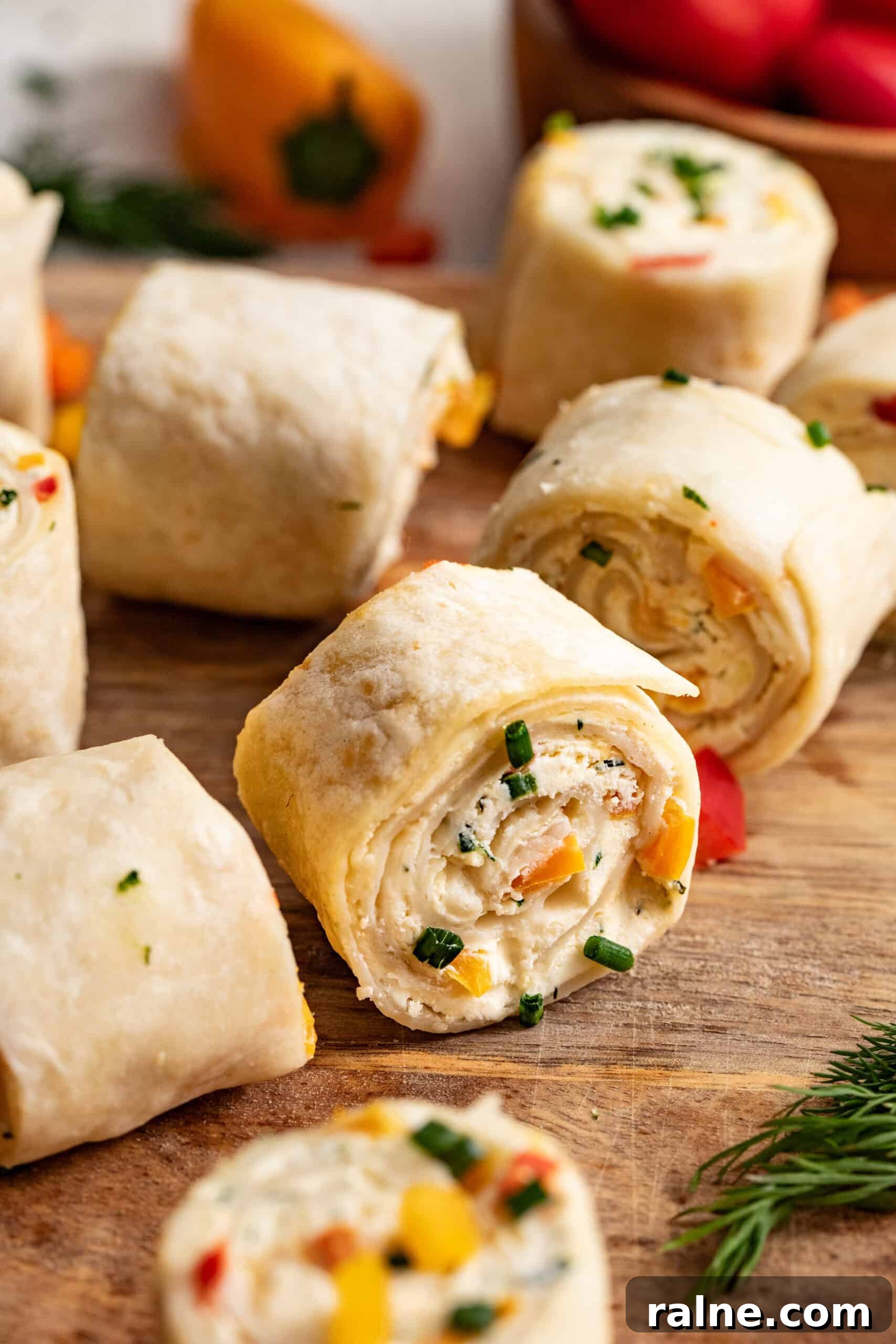 Cream Cheese Tortilla Roll-Ups: 5-Minute Party Appetizer Recipe 6 Tortilla roll ups on a cutting board, stuffed with peppers and cream cheese.